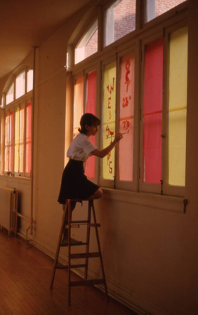 Female student paints a window
